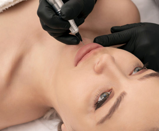Cosmetologist applying permanent tattoo make up on lips Cosmetologist applying permanent make up on the lips