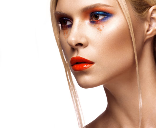 Beautiful girl with bright colored makeup and orange lips. Beauty the face. Photos shot in studio