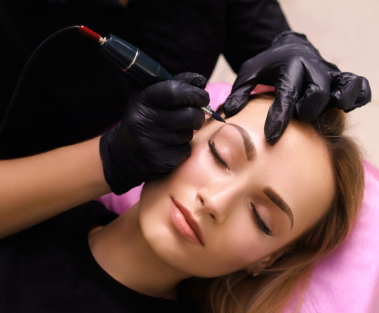 Permanent make up on eyebrows. Cosmetologist applying permanent make up on eyebrows- eyebrow tattoo.