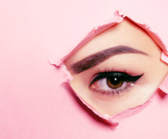 Beautiful brown eye, arrows, perfect eyebrows. Beauty salon, eyebrow master, tattoo master shooter and eyebrow. Beautiful eye on a pink background.